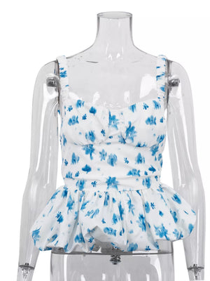 White peplum top with blue floral print, sweetheart neckline, and ruffled straps.