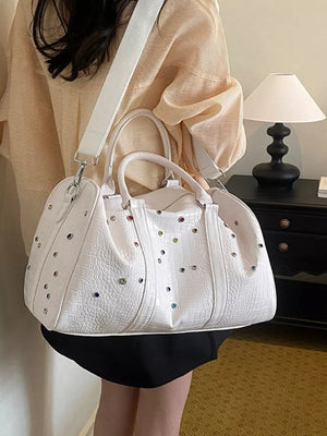White crocodile textured duffel bag with colorful studs and detachable strap
