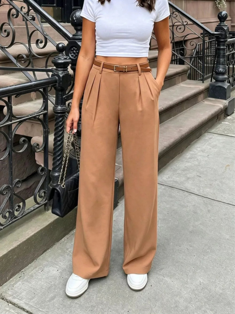 Brown pleated wide-leg pants with a belted waist and a brown leather belt.