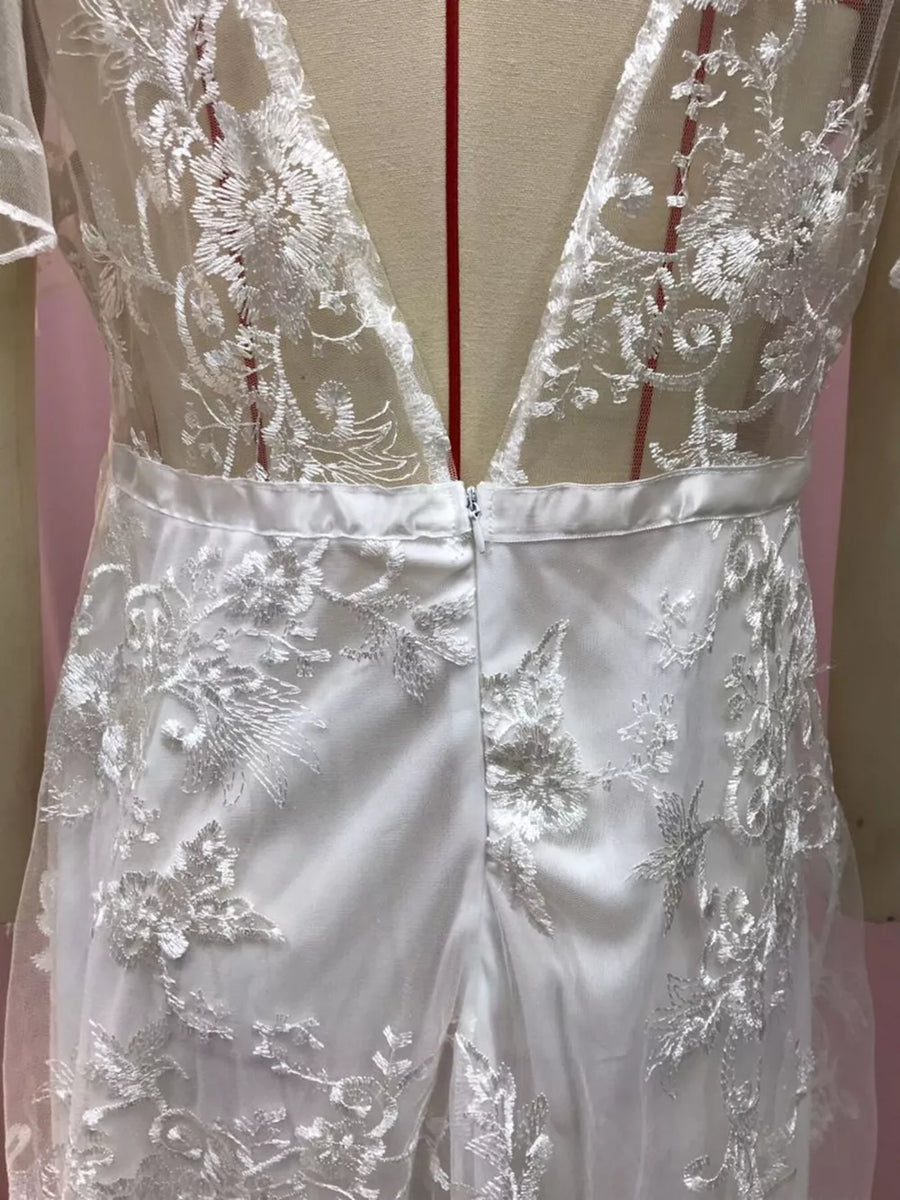 White lace flutter sleeve v-neck dress with satin waistband and floral embroidery.