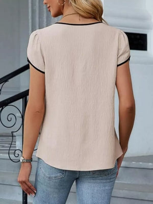 Apricot blouse with black trim, petal sleeves, and textured fabric.