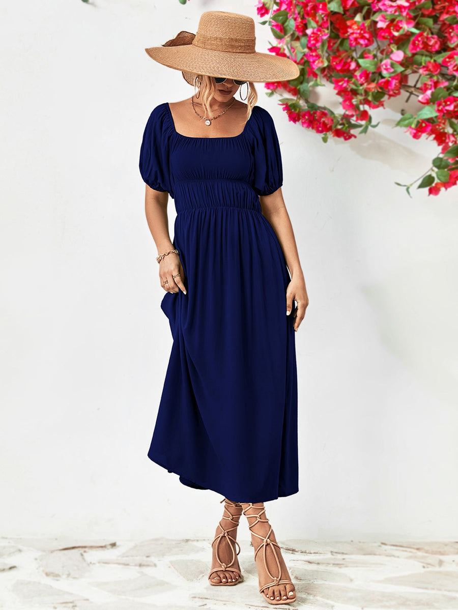 Dark blue midi dress with gathered bodice, square neckline, and puff sleeves.