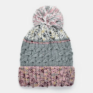 Textured cable knit beanie with a multicolor pompom and pink trim.