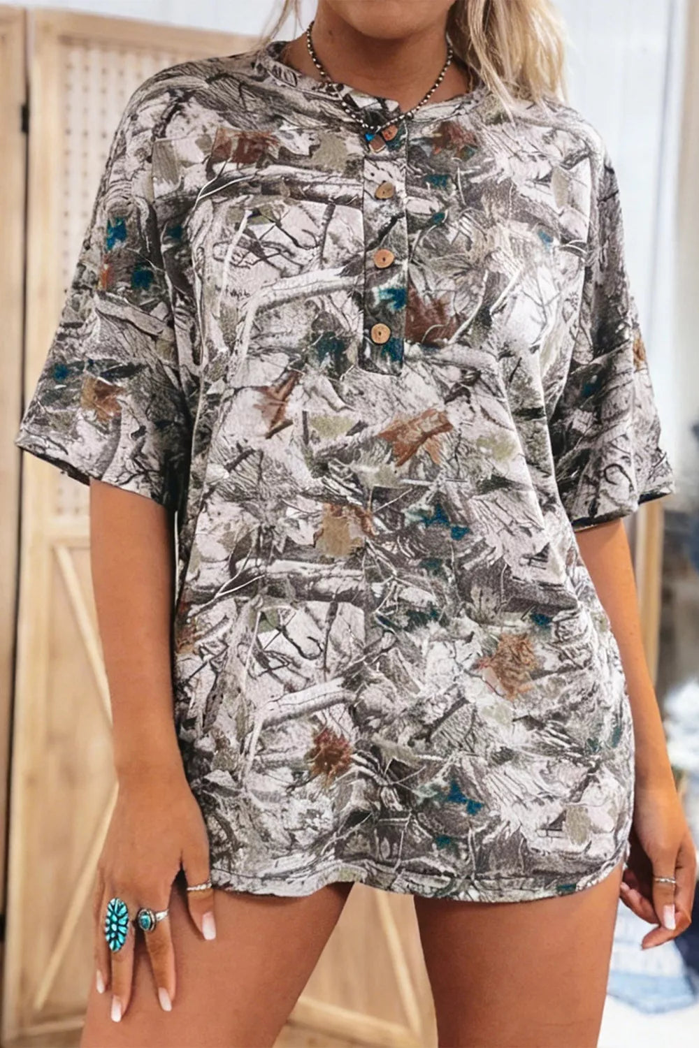 Earthy camouflage print henley t-shirt with button detail and short sleeves.
