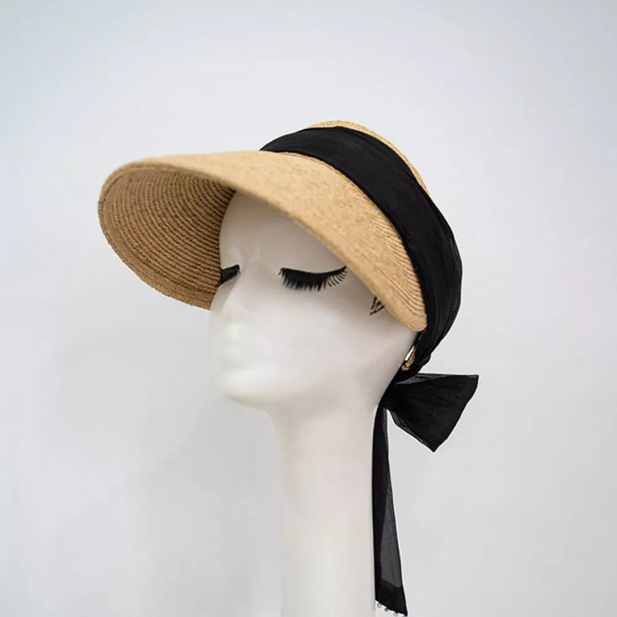 Straw visor hat with black ribbon tie and beaded detail.