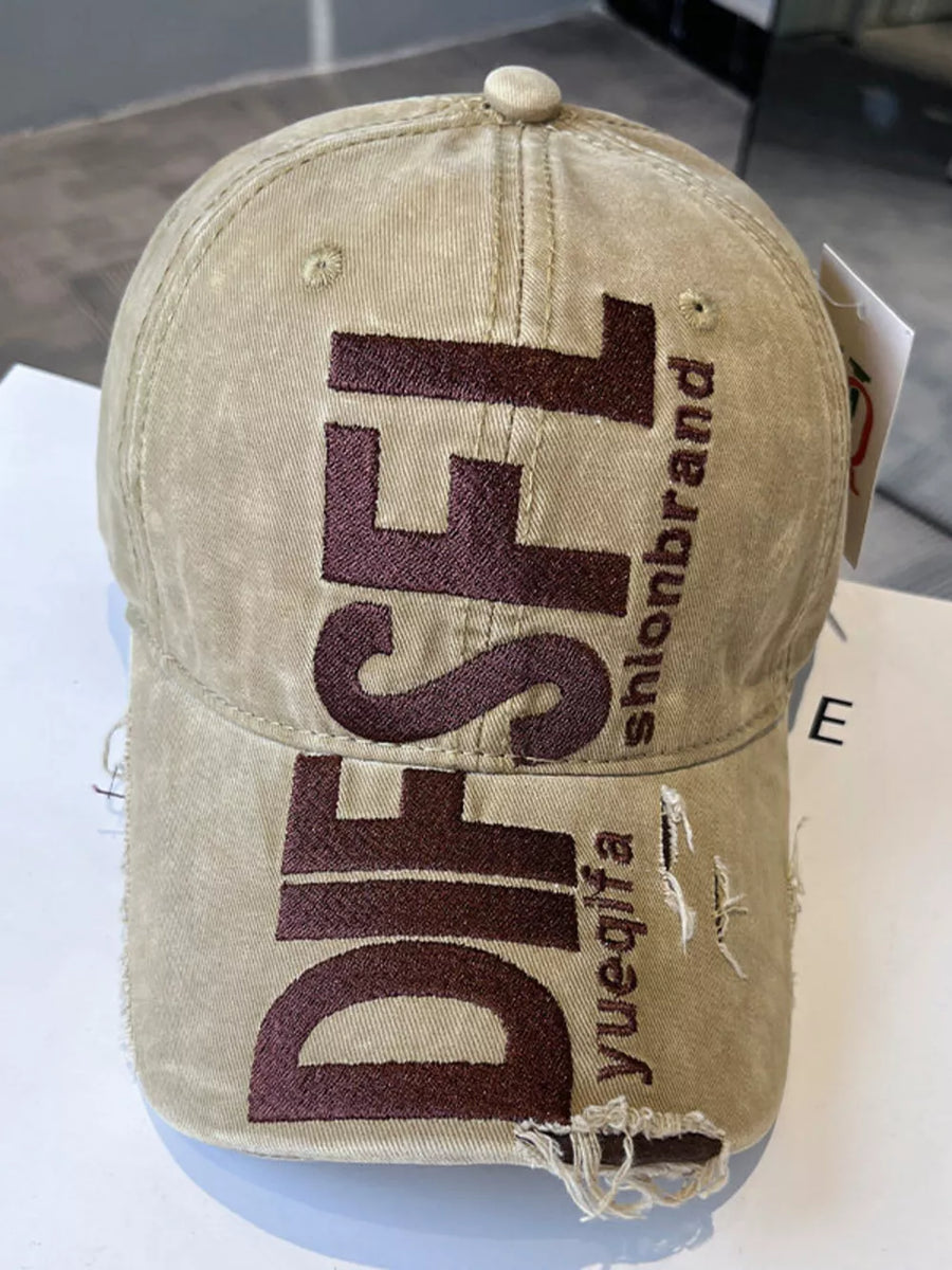 Beige distressed baseball cap with large dark brown embroidered text and frayed details.