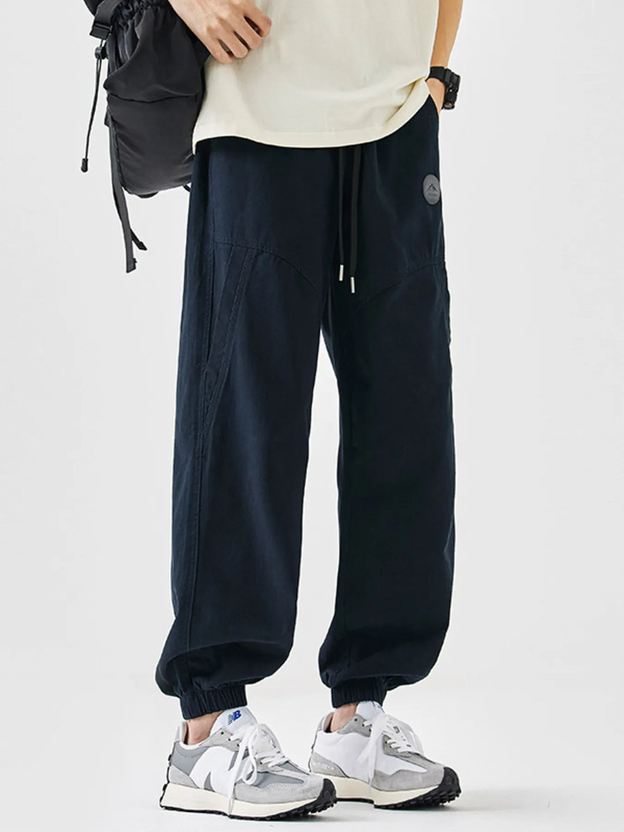 Navy blue relaxed fit joggers with drawstring and cuffed ankles, featuring a small logo patch.
