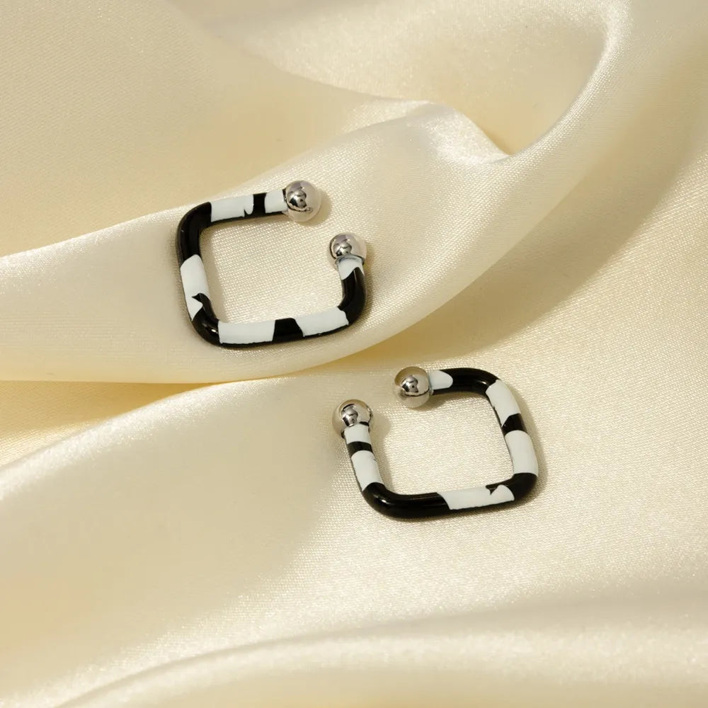 Geometric zebra stripe ear cuffs with silver ball details on a satin background.