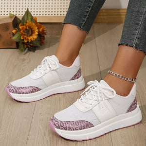 White lace-up sneakers with pink text detail on the sole and heel.