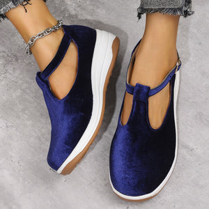 Blue velvet T-bar flat slip-ons with adjustable strap and white sole.