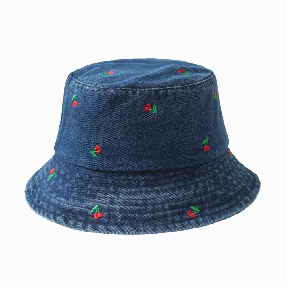 Denim bucket hat with allover red cherry embroidery and a stitched brim.