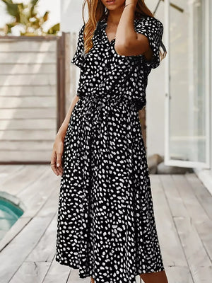Black polka dot midi dress with short sleeves, collared neckline, and cinched waist.