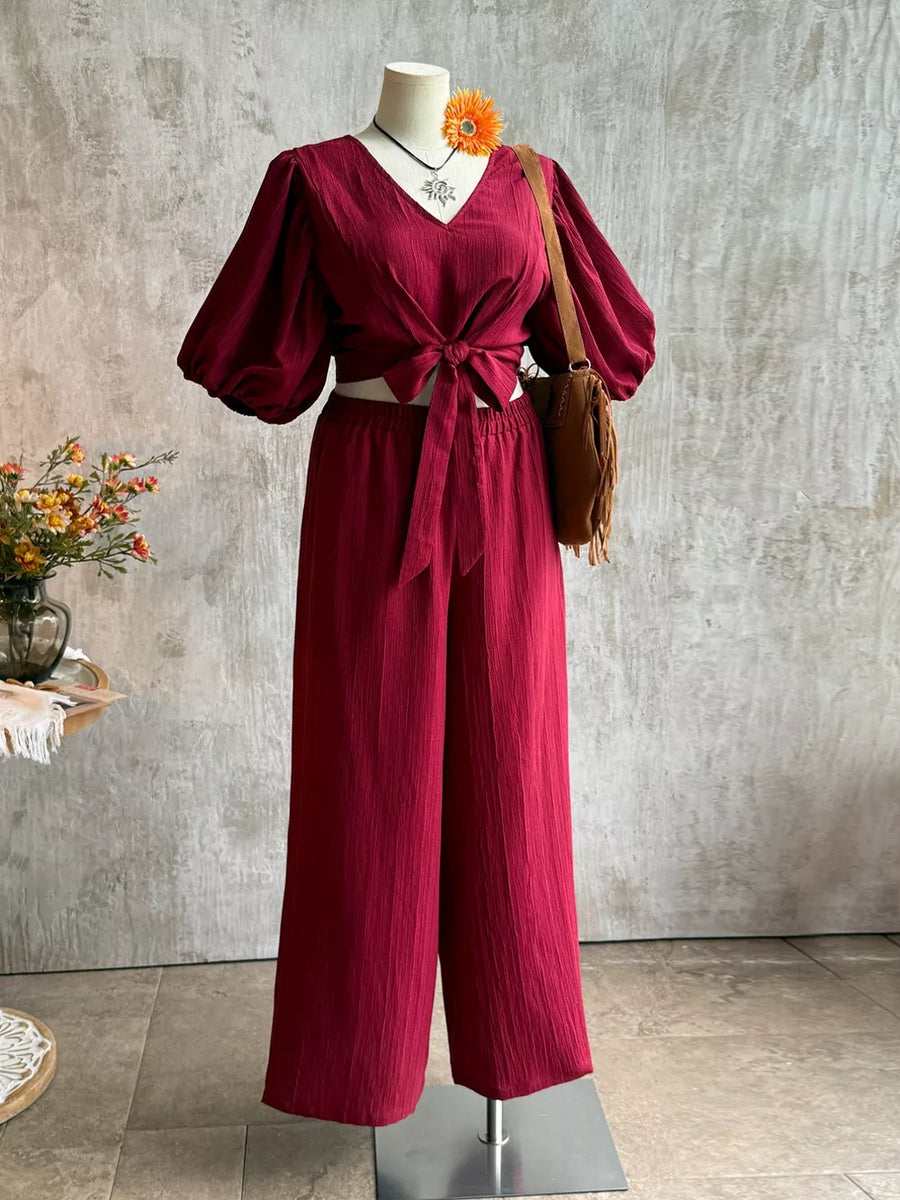 Deep red textured tie-front crop top with balloon sleeves and wide-leg pants set.