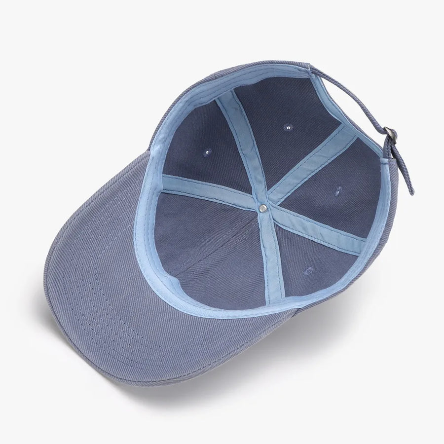 Textured denim baseball cap in Dusty Blue, showing interior construction and adjustable strap.