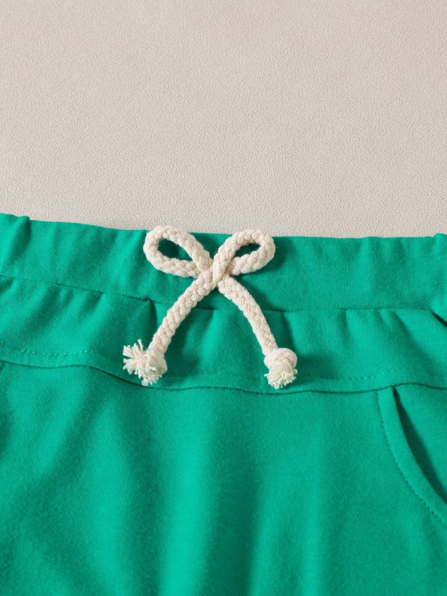 Green baby set shorts with drawstring waist and pocket detail.