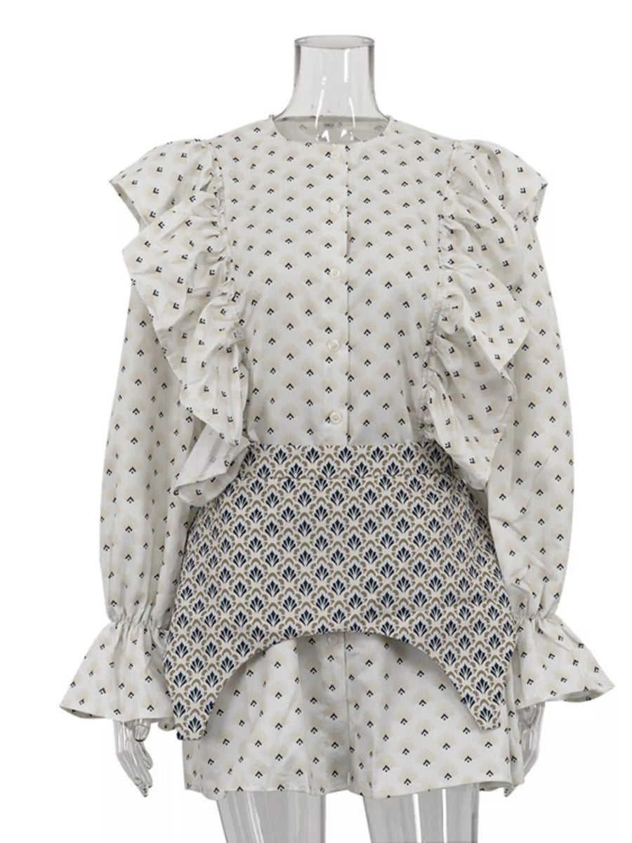 White patterned blouse with ruffled sleeves and a contrasting patterned peplum waist.