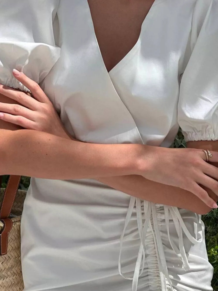 White wrap dress with V-neck, puff sleeves, and ruched drawstring detail