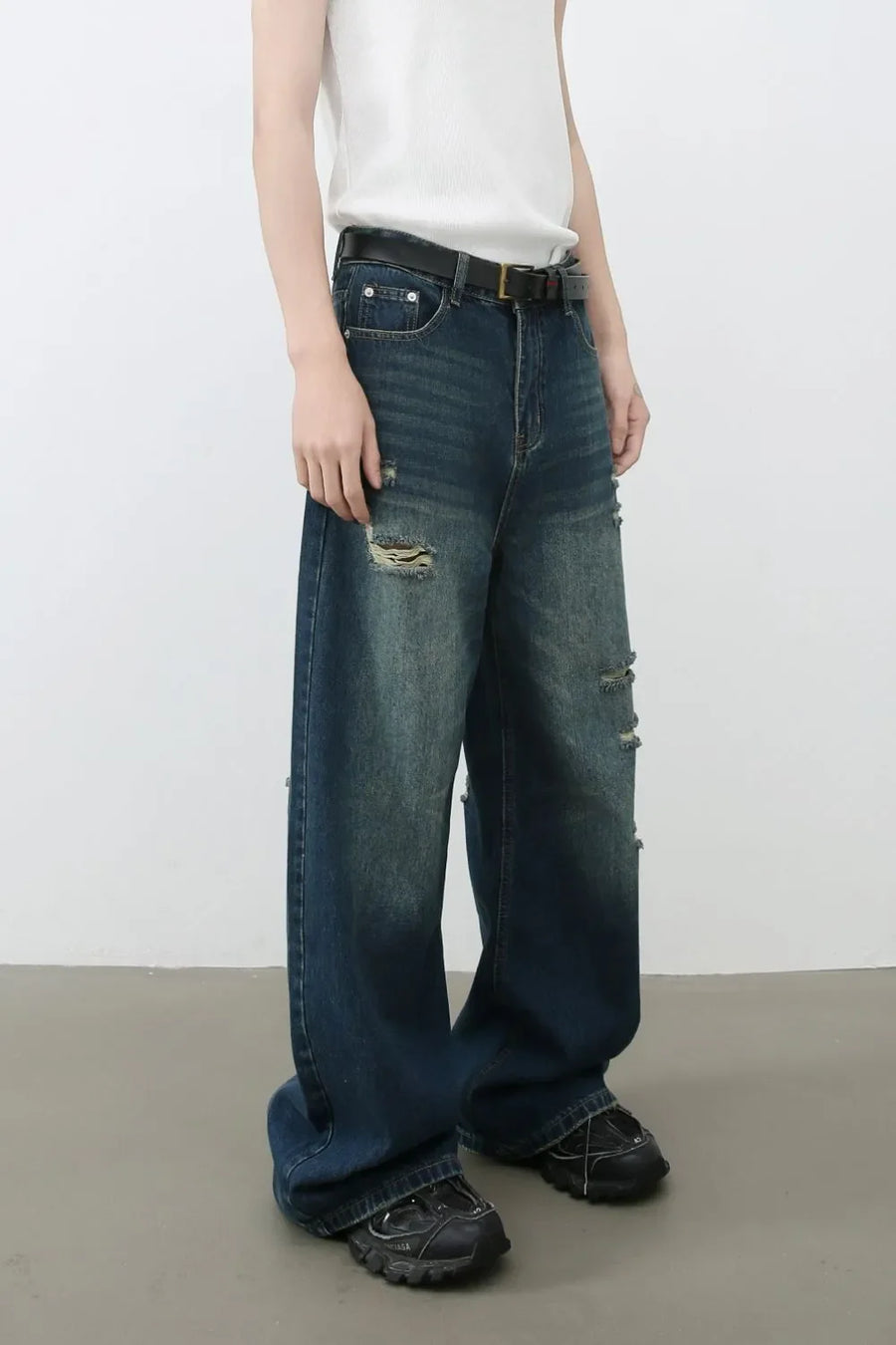 Distressed baggy dark wash denim jeans with ripped details and a relaxed fit.