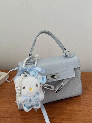 Pastel blue croc-embossed mini crossbody bag with a fluffy white charm and pearl strap.