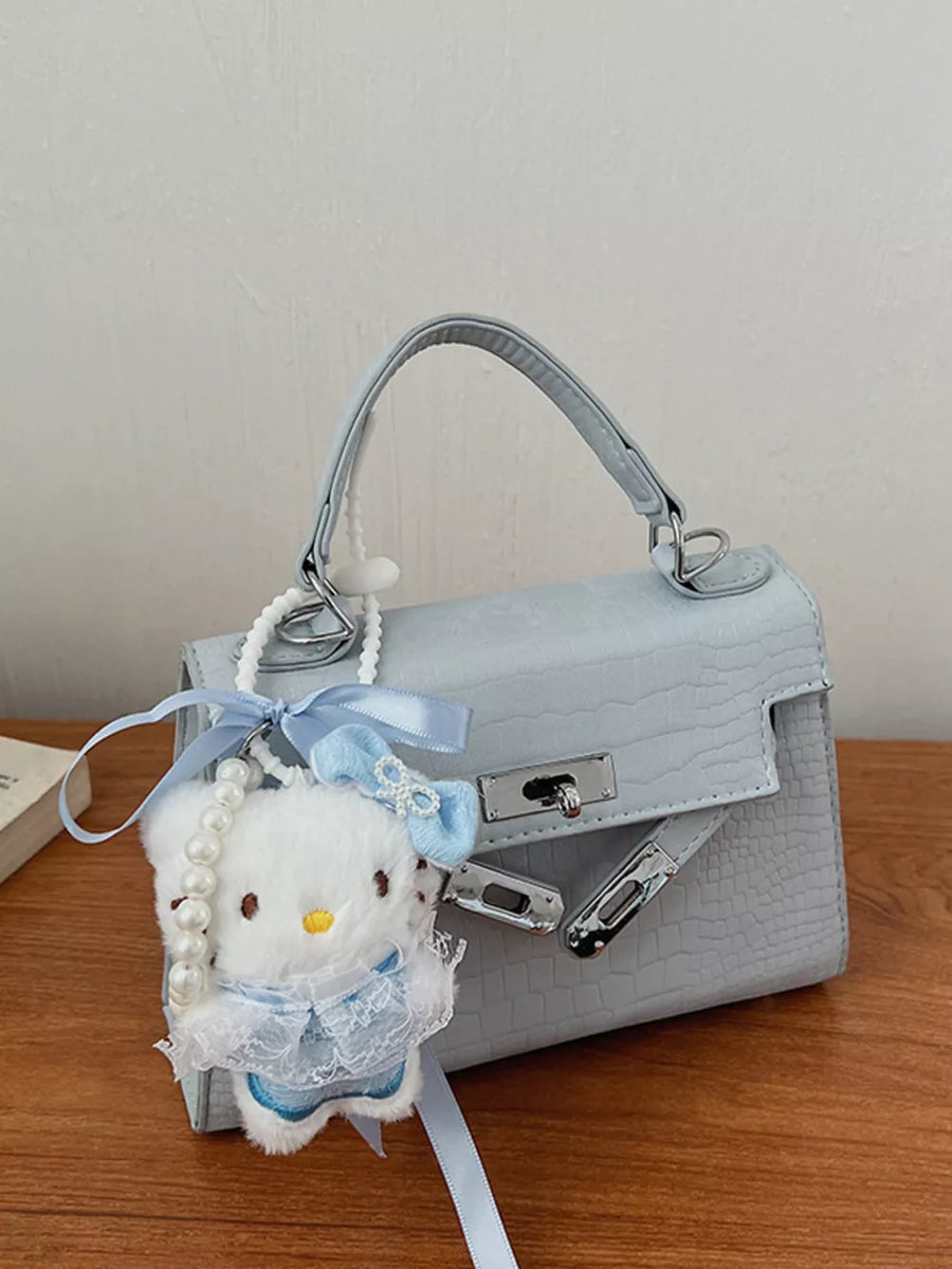 Pastel blue croc-embossed mini crossbody bag with a fluffy white charm and pearl strap.