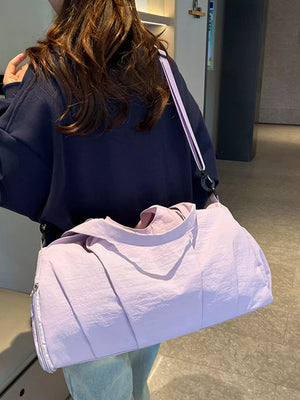 Duffel bag in light purple crinkled fabric with a zipper closure and adjustable strap.