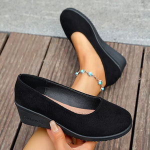 Black textured round toe wedge slip-ons with a low wedge heel.