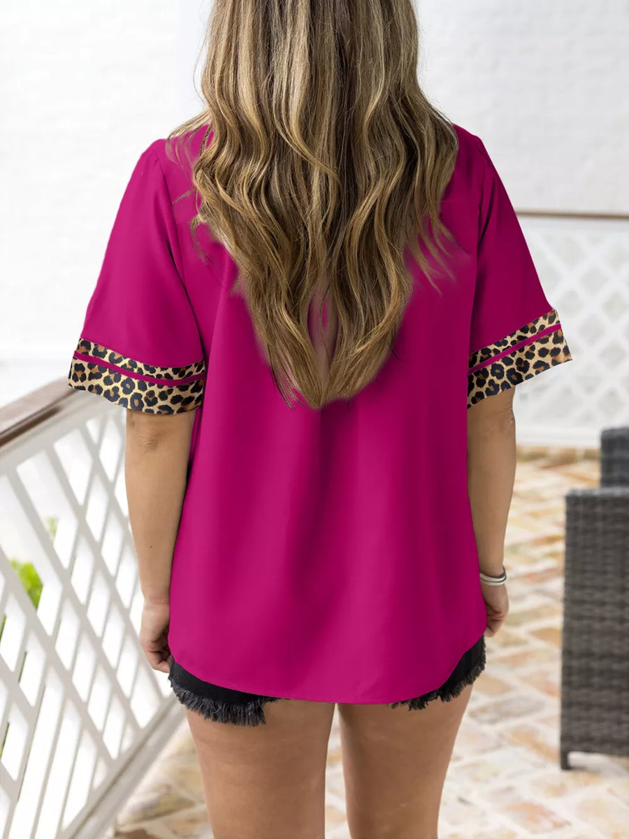Pink split neck blouse with leopard trim on sleeves.