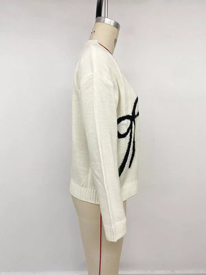 Cream knit sweater with black bow graphic, crew neck, long sleeves.