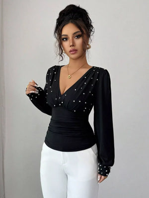 Black ruched V-neck blouse with pearl embellishments and long sleeves.