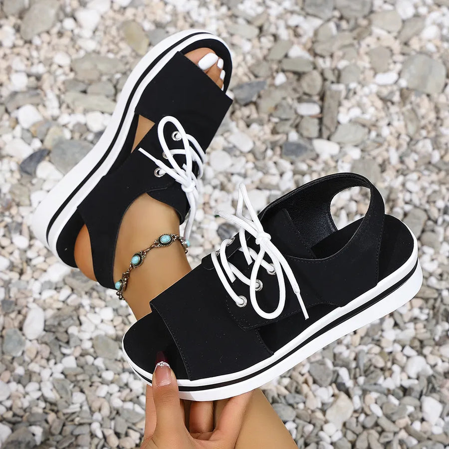 Black platform oxford sandals with white laces and white striped soles.