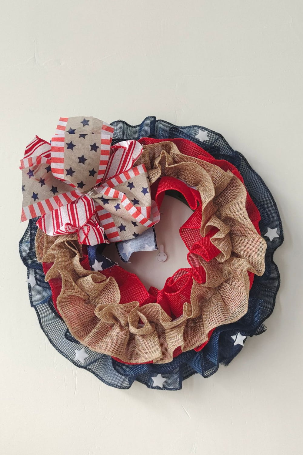 Patriotic ruffled burlap wreath with red, white, and blue stars and stripes bow.