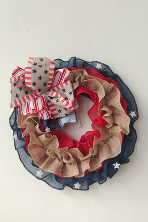 Patriotic ruffled burlap wreath with red, white, and blue stars and stripes bow.
