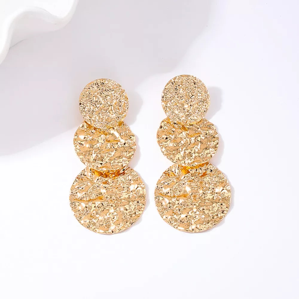 Golden earrings featuring layered and textured