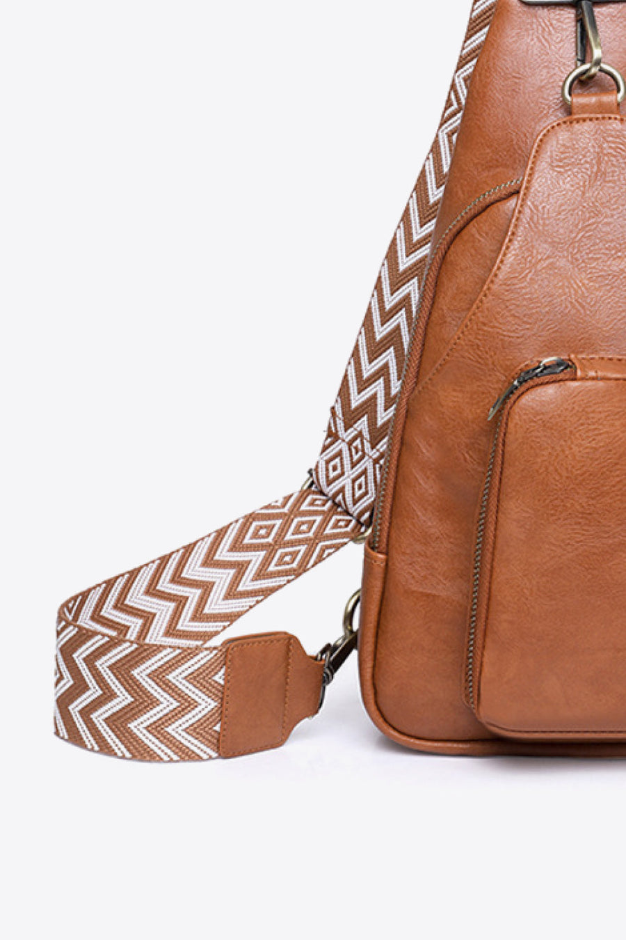 Honey PU sling bag with geometric patterned strap and zipper pocket detail.