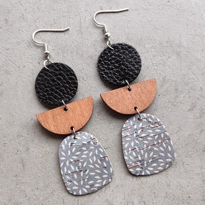 Geometric layered leather and wood earrings with a gray patterned cork bottom.