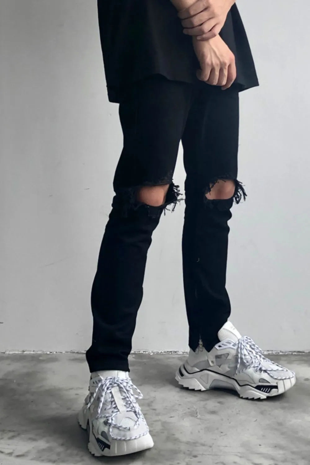 Black skinny fit denim jeans with distressed knee details.