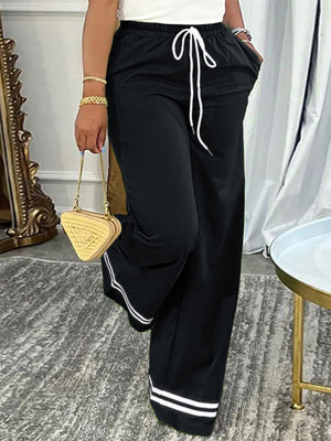 Black wide-leg pants featuring drawstring waist and striped