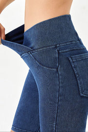 Medium wash denim bermuda shorts with a high rise crisscross waistband and pocket details.