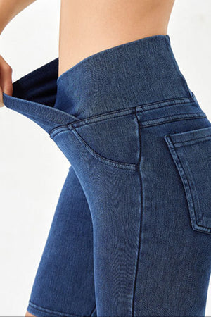 Medium wash denim bermuda shorts with a high rise crisscross waistband and pocket details.