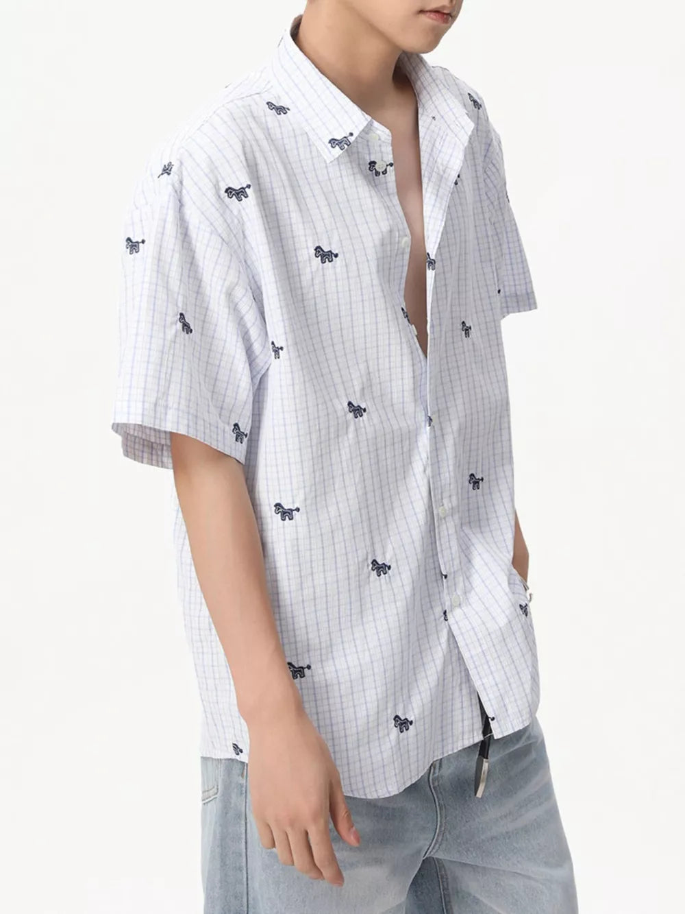 White short sleeve button up shirt with blue plaid and embroidered animal motifs.