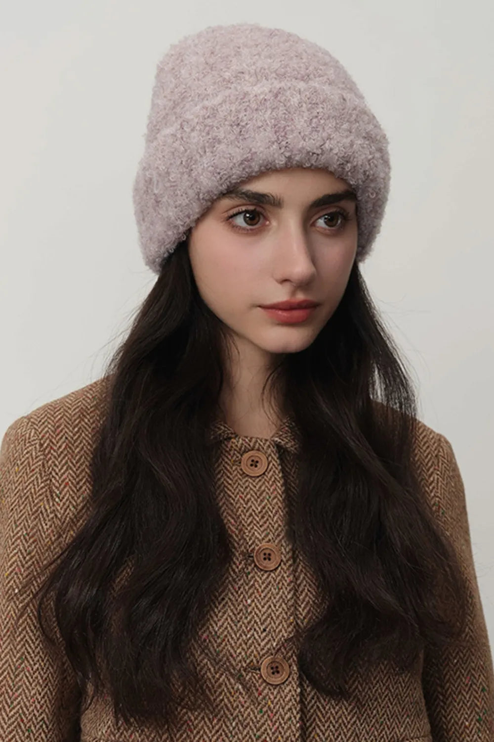 Mauve textured bouclé knit beanie on a woman wearing a brown herringbone jacket.