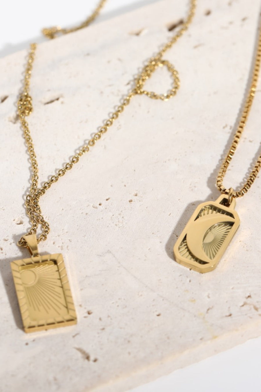 18K gold-plated celestial pendant necklaces, one with a sun, one with a moon, on delicate chains.