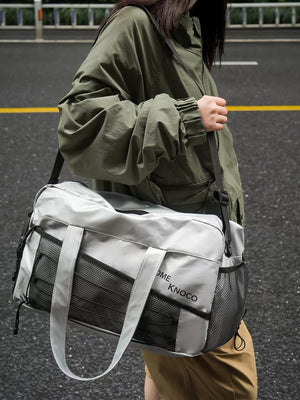 Sleek silver duffel bag with mesh pockets and adjustable strap.