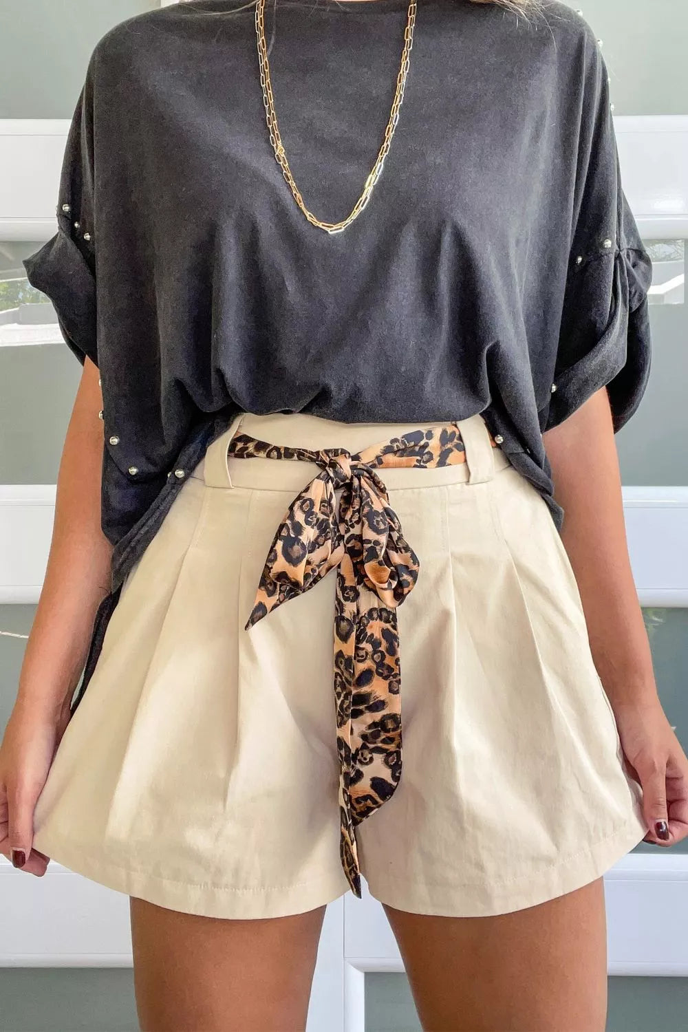 Cream pleated shorts with leopard print tie belt and pearl-embellished charcoal t-shirt
