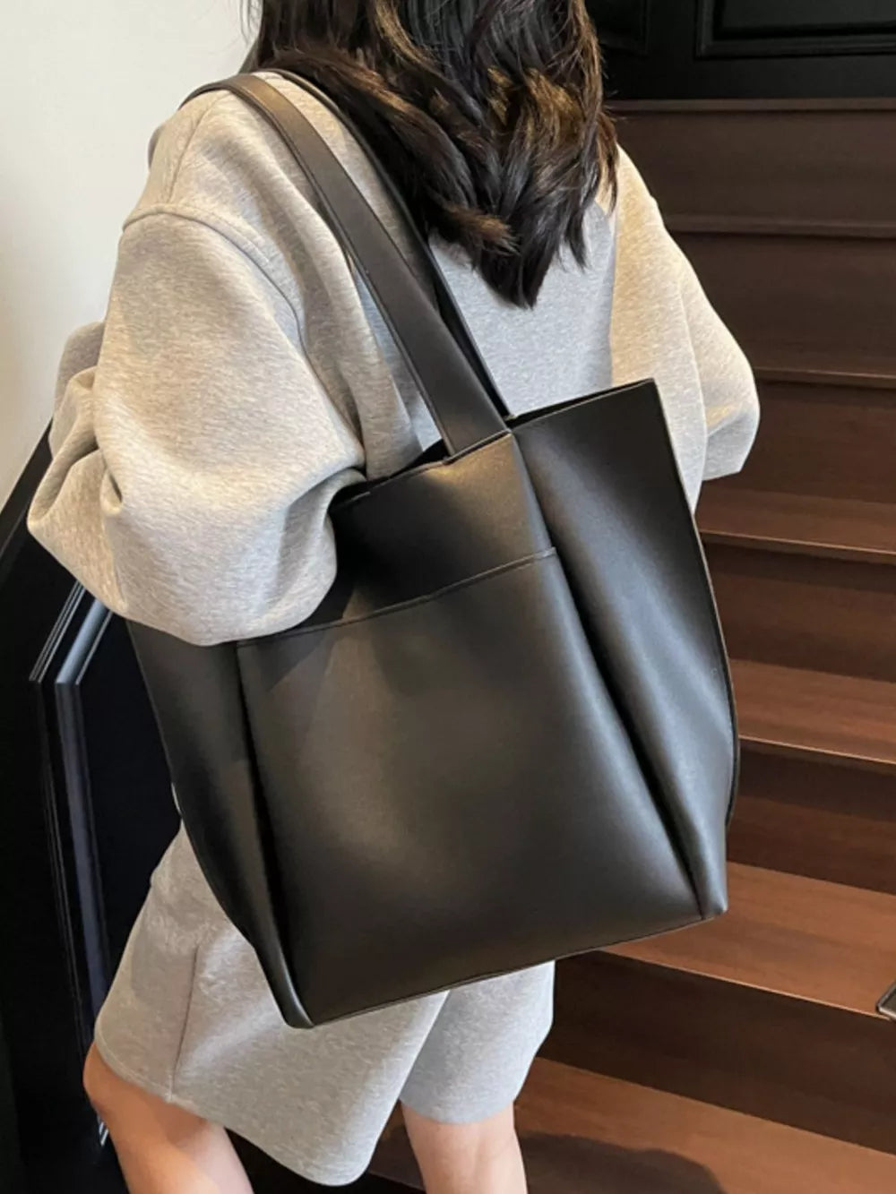 Black pu leather tote bag with a minimalist design and shoulder strap.