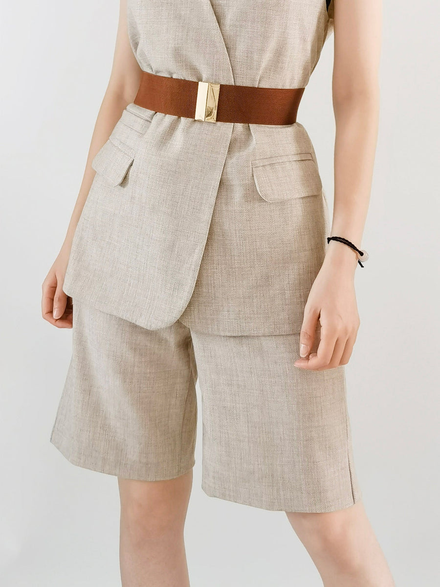 Wide elastic belt in tan with a gold clasp, cinching a linen blend vest and shorts.