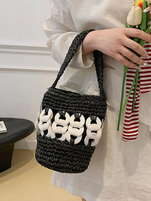 Black woven straw bucket tote with white ring detail and braided strap.