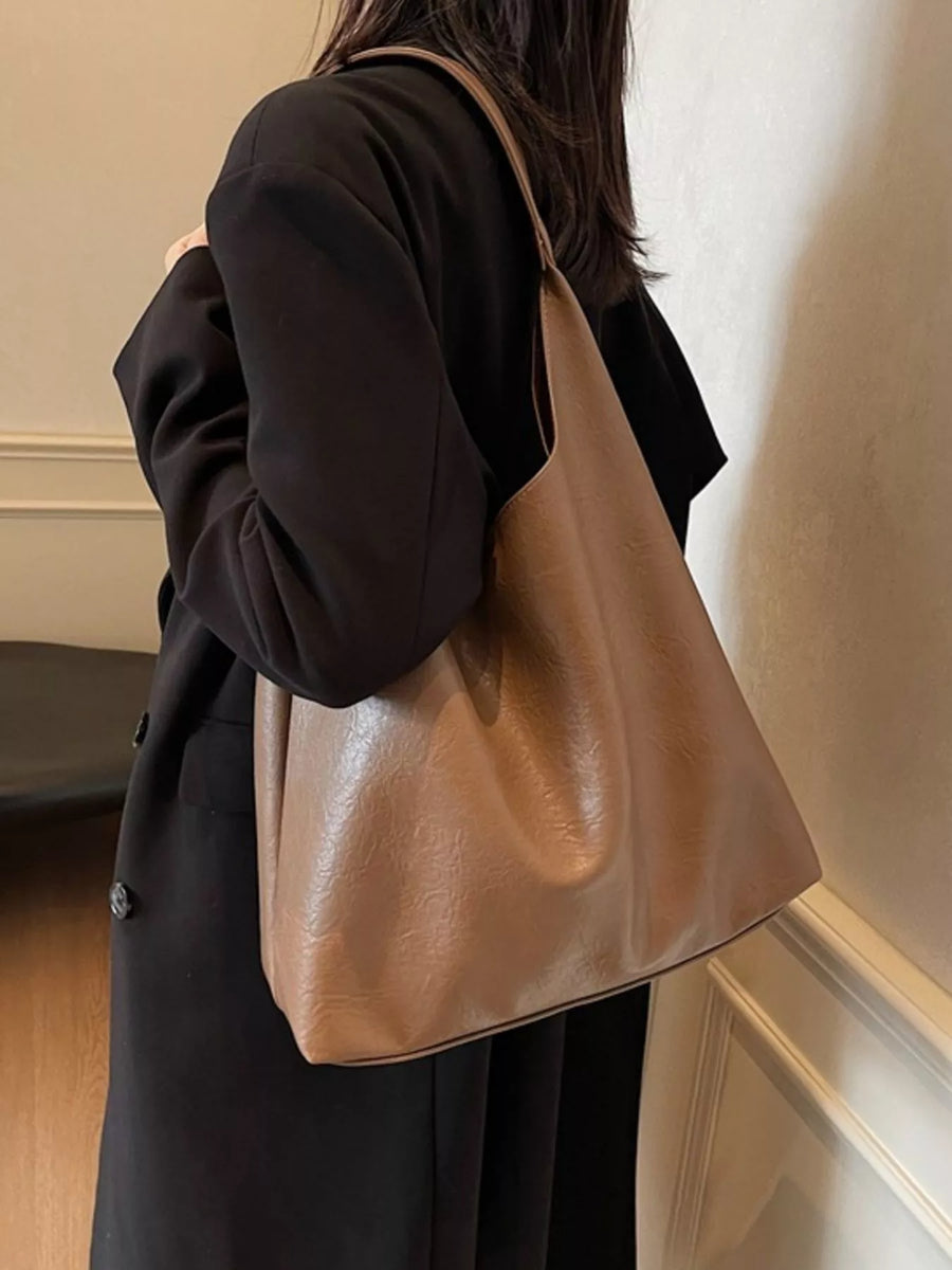 Sculptural PU leather tote bag in brown with a slouchy silhouette and shoulder strap.