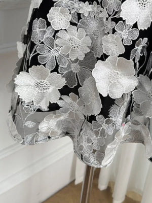 Black dress with white floral lace overlay and embroidered details.