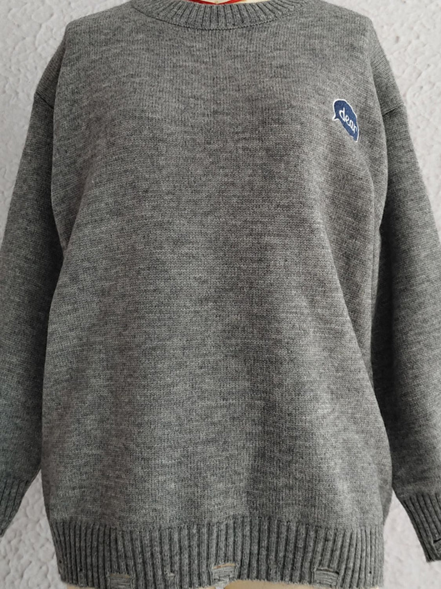 Dark gray acrylic knit sweater with embroidered blue oval detail and distressed hem.